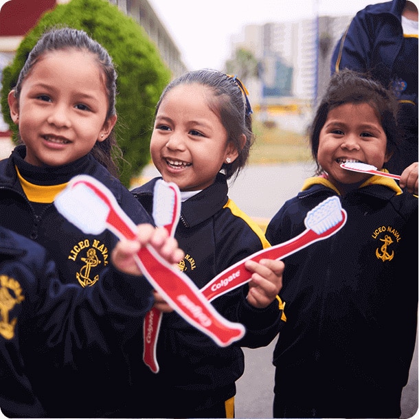 tres niños sonrientes con cepillos de dientes de juguete